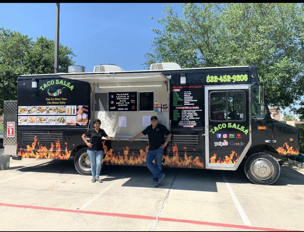 A man and a woman posing in front of Taco Salsa's Black truck